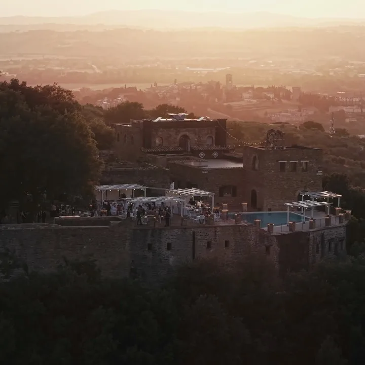 Il Castello di Rosciano al tramonto visto dall'alto, con gli ospiti sulla terrazza e la valle umbra sullo sfondo