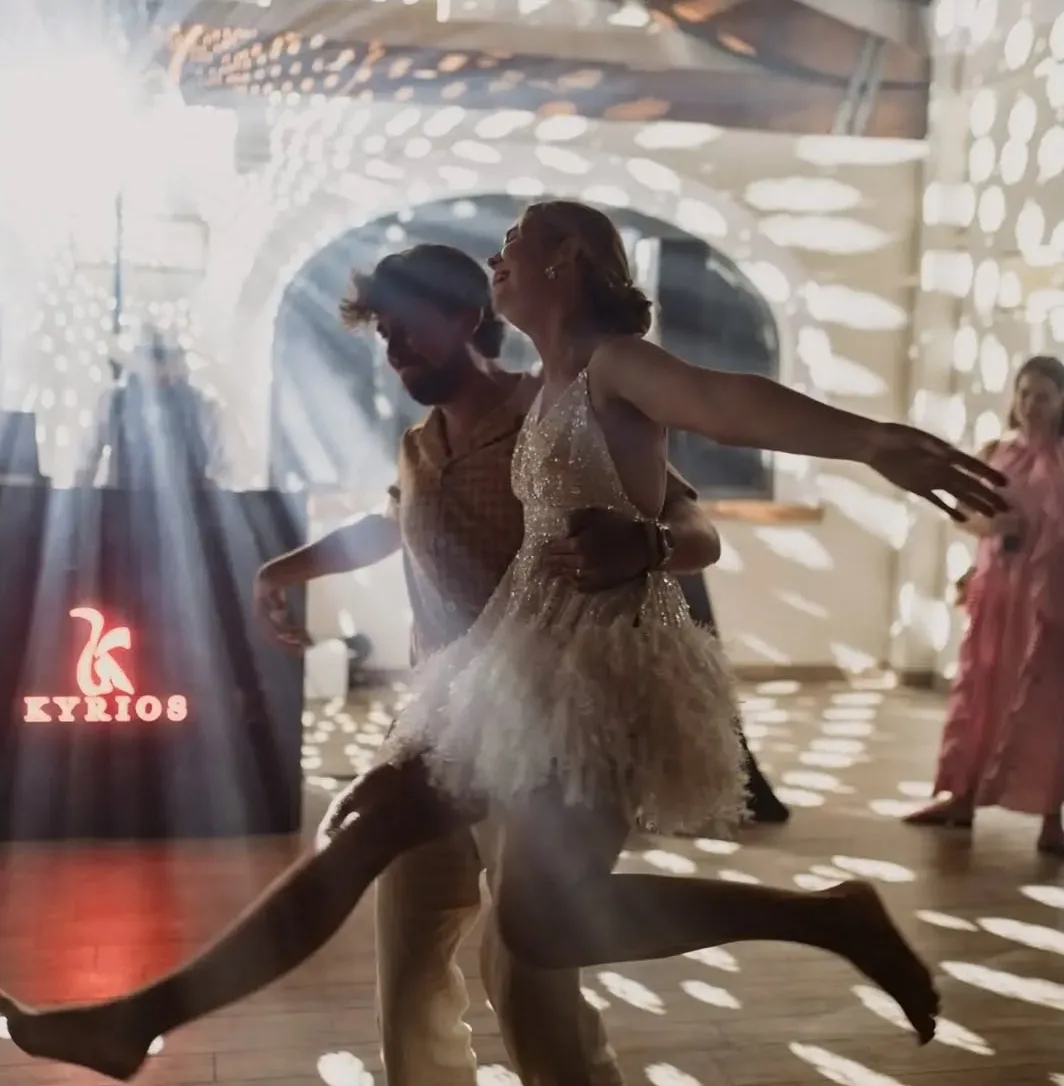 Sposi che ballano a piedi nudi sotto le luci da discoteca, con l'insegna luminosa Kyrios sullo sfondo